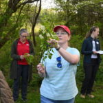 A teacher outside pointing to leaves on a branch