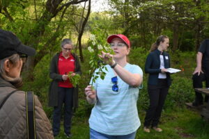 A teacher outside pointing to leaves on a branch